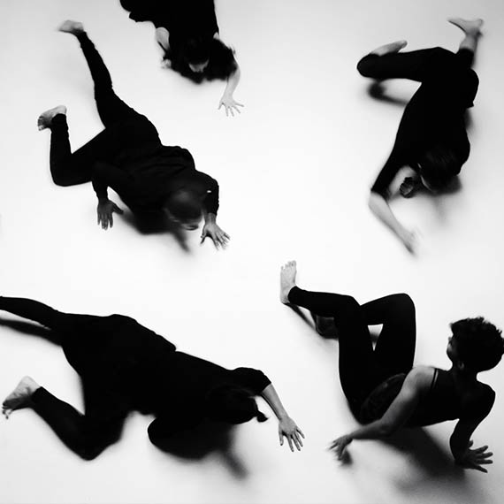 Dancers dress in black crawling towards singer in music video