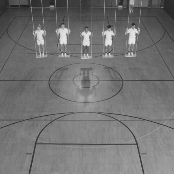 Five dancers in  white shirt and shorts on swings in gymnasiums for a Converse commercial
